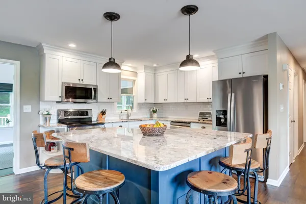 a kitchen with stainless steel appliances granite countertop a sink a stove a refrigerator a dining table and chairs with wooden floor