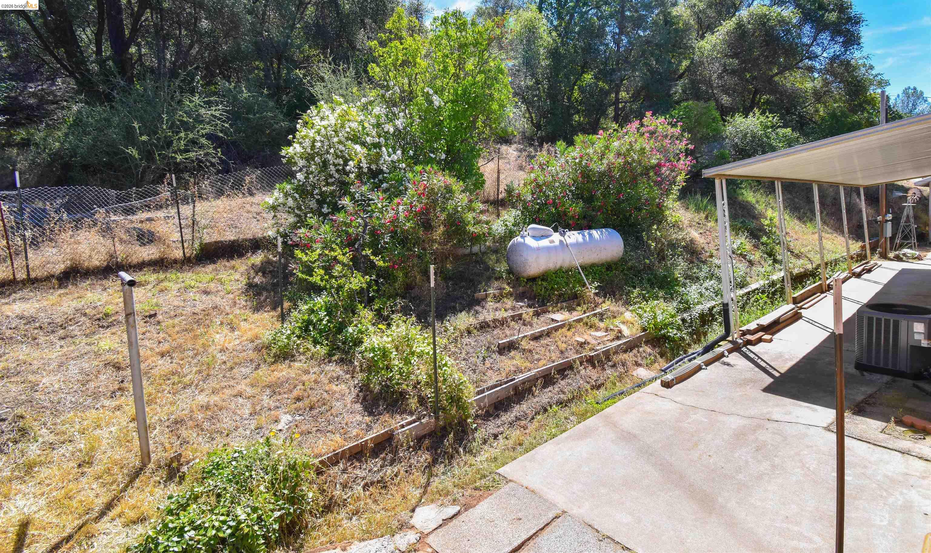 13904 Tuolumne Road Sonora, CA 95370 - Photo 32 of 44 Paved concrete patio and walkway, featuring an attached carport structure with a metal roof