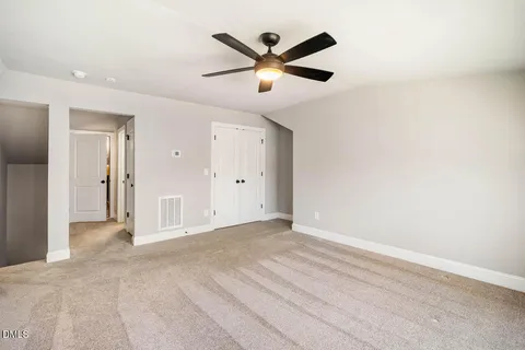 an empty room with closet and ceiling fan