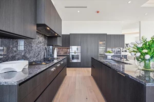 a kitchen with stainless steel appliances granite countertop a sink a stove and a wooden floors