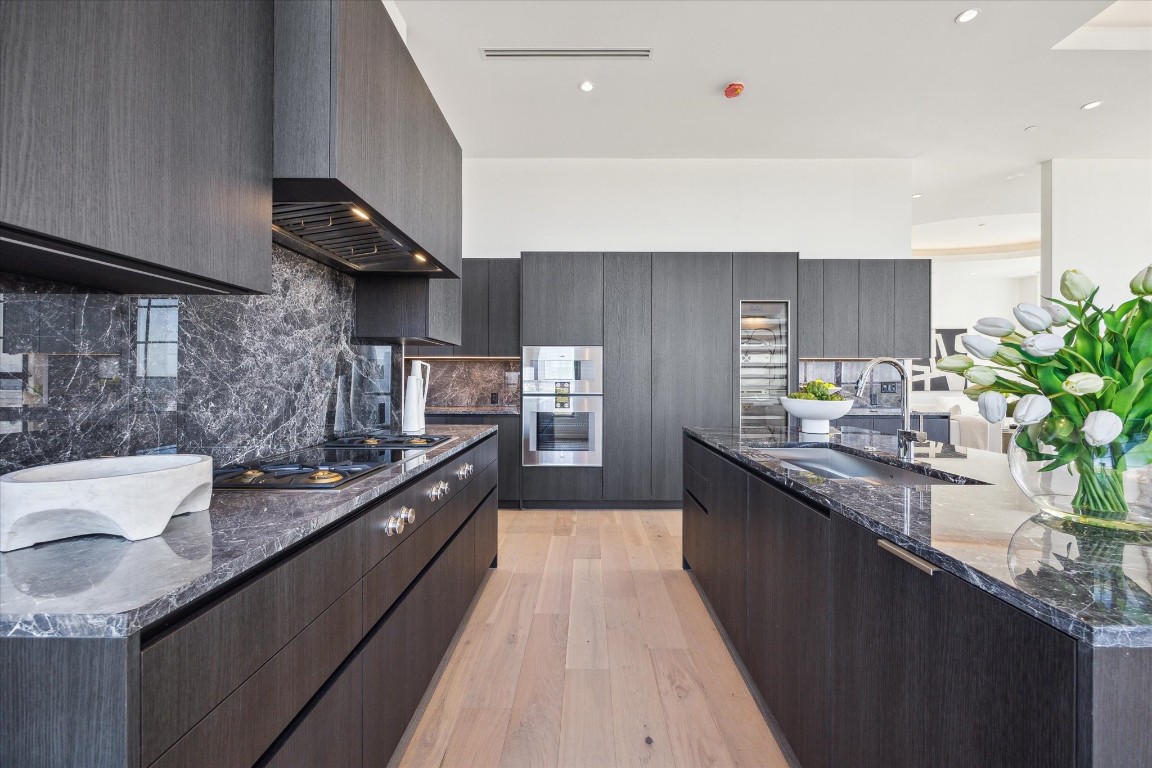 2323 San Felipe Street, Unit 1101 Houston, TX 77019 - Photo 6 of 24 a kitchen with stainless steel appliances granite countertop a sink a stove and a wooden floors