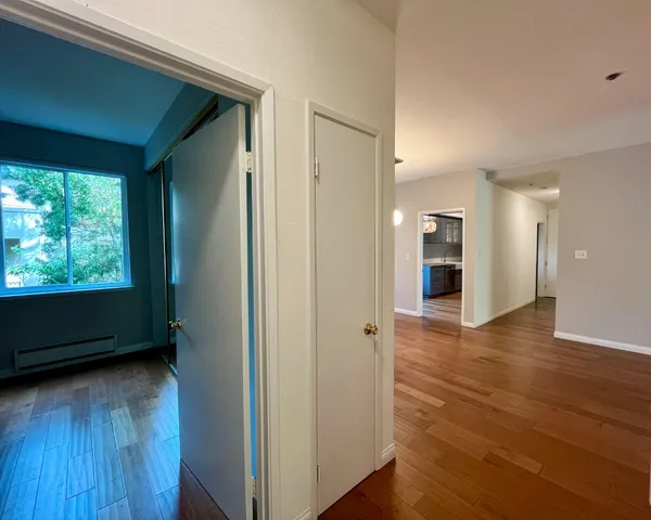 a view of hallway with a large window and wooden floor