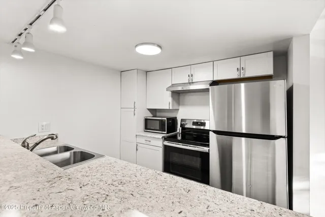 a kitchen with granite countertop a refrigerator and a sink