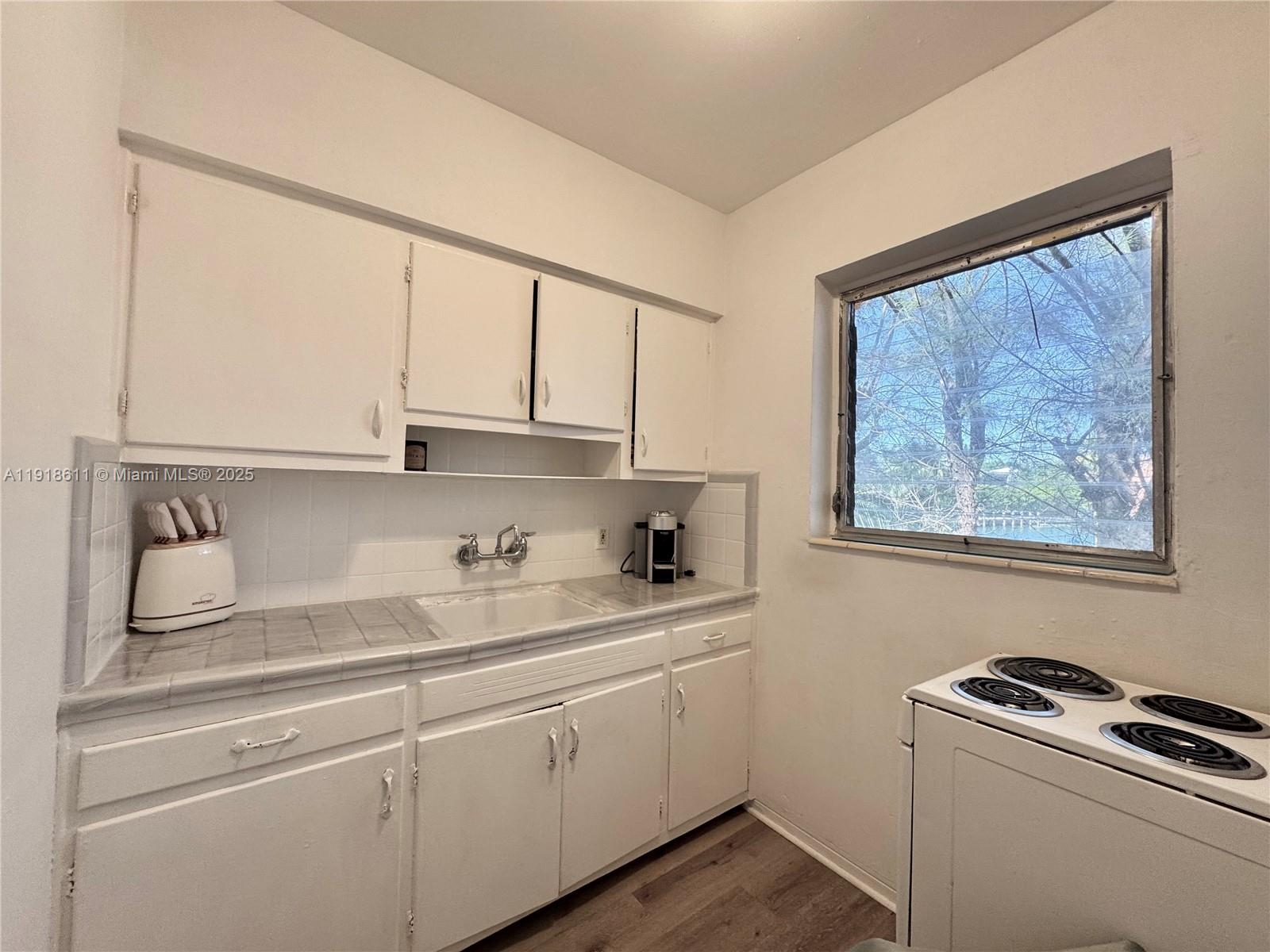 4740 Pine Tree Drive, Unit 32 Miami Beach, FL 33140 - Photo 17 of 20 a kitchen with a sink cabinets and window