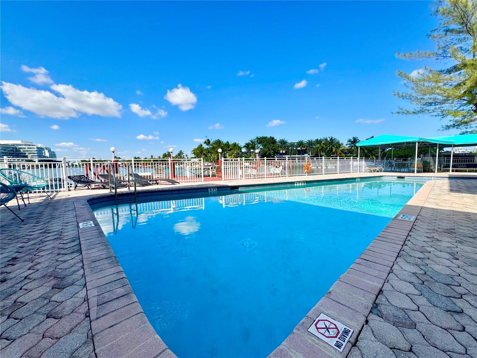 4740 Pine Tree Drive, Unit 32 Miami Beach, FL 33140 - Photo 3 of 20 a view of a swimming pool and lounge chairs