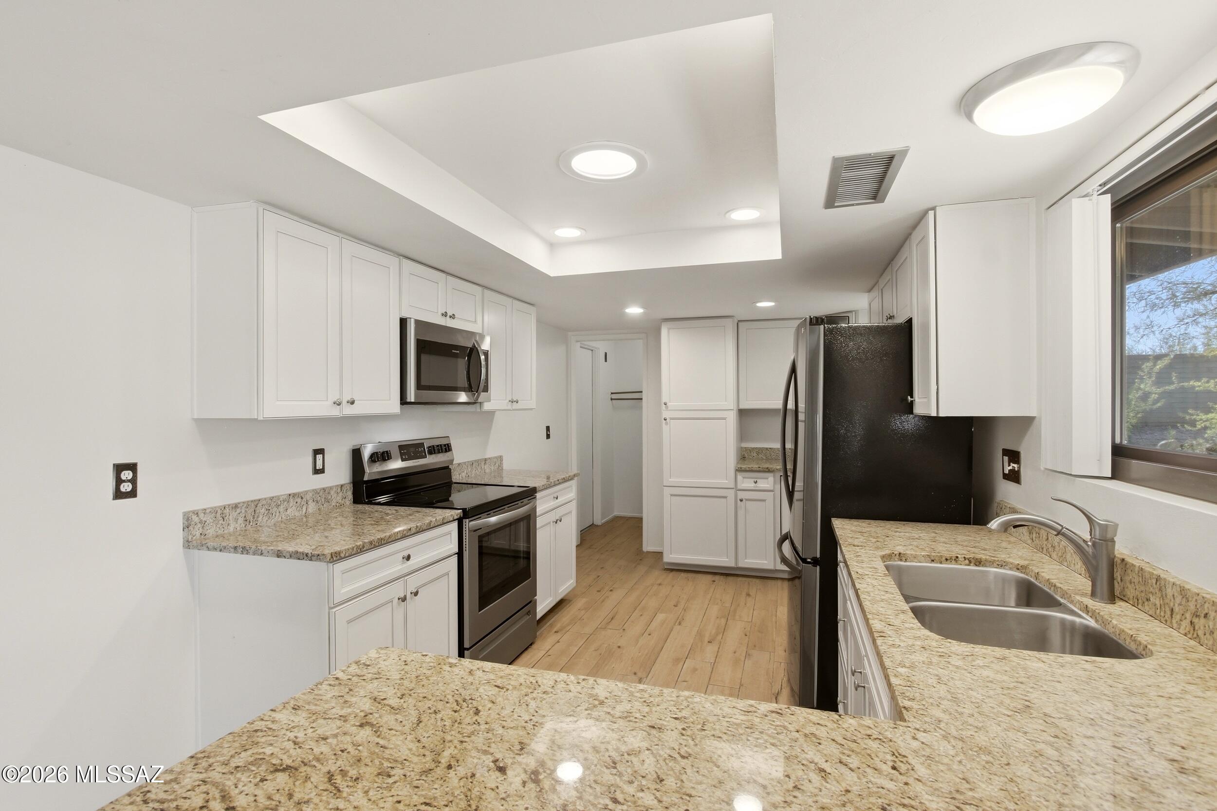 9141 East Indian Canyon Road Tucson, AZ 85749 - Photo 11 of 33 a kitchen with granite countertop a sink a counter top space appliances and cabinets