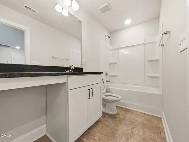 a bathroom with a granite countertop sink a toilet and shower