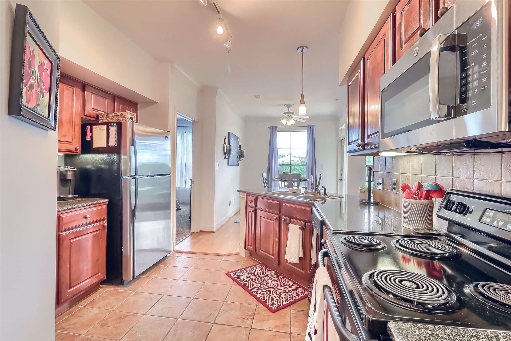7701 Rialto Boulevard, Unit 1128 Austin, TX 78735 - Photo 6 of 35 a kitchen with stainless steel appliances granite countertop a stove top oven a sink and a refrigerator