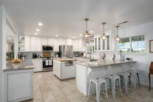 a kitchen with white cabinets and chairs