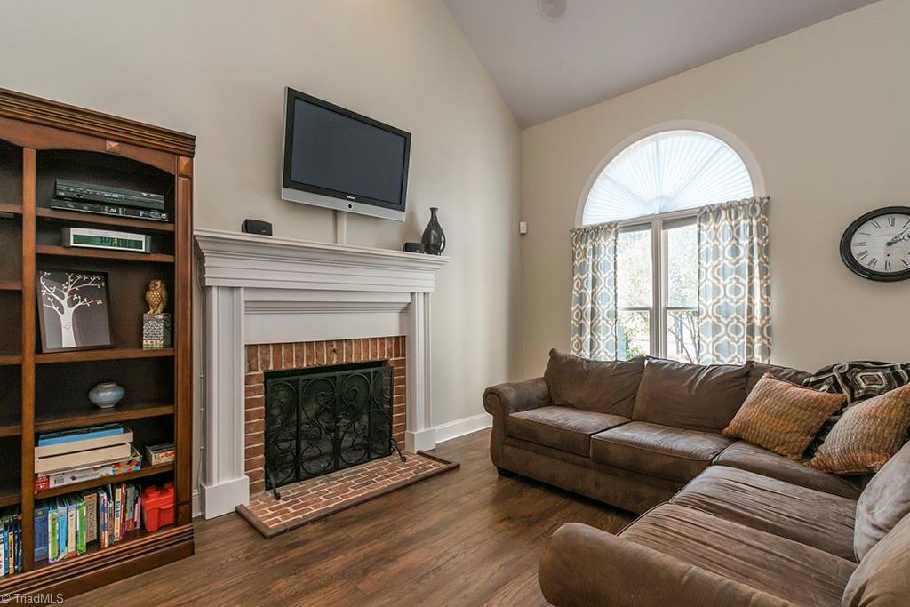 3101 Spring Mill Road Greensboro, NC 27406 - Photo 5 of 30 Warm and inviting living room with fireplace focal point and Armstrong barrel oak wood plank laminate flooring. Tons of light from lthe large window.