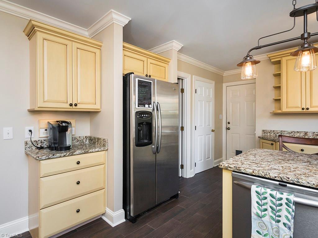 3101 Spring Mill Road Greensboro, NC 27406 - Photo 10 of 30 Kitchen, the gathering place! 1/2 bath and Laudry entry are to the right of the Fridge Notice the bar area with stools and updated gorgeous granite as well as the stainless steel appliances. Lots of cabinet space - including - notice the kitchen side bar cabinets behind the stool.