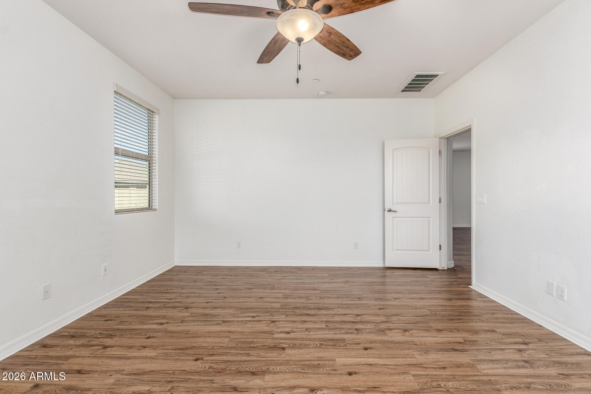 21294 West Berkeley Road Buckeye, AZ 85396 - Photo 15 of 34 a view of an empty room with wooden floor and a ceiling fan
