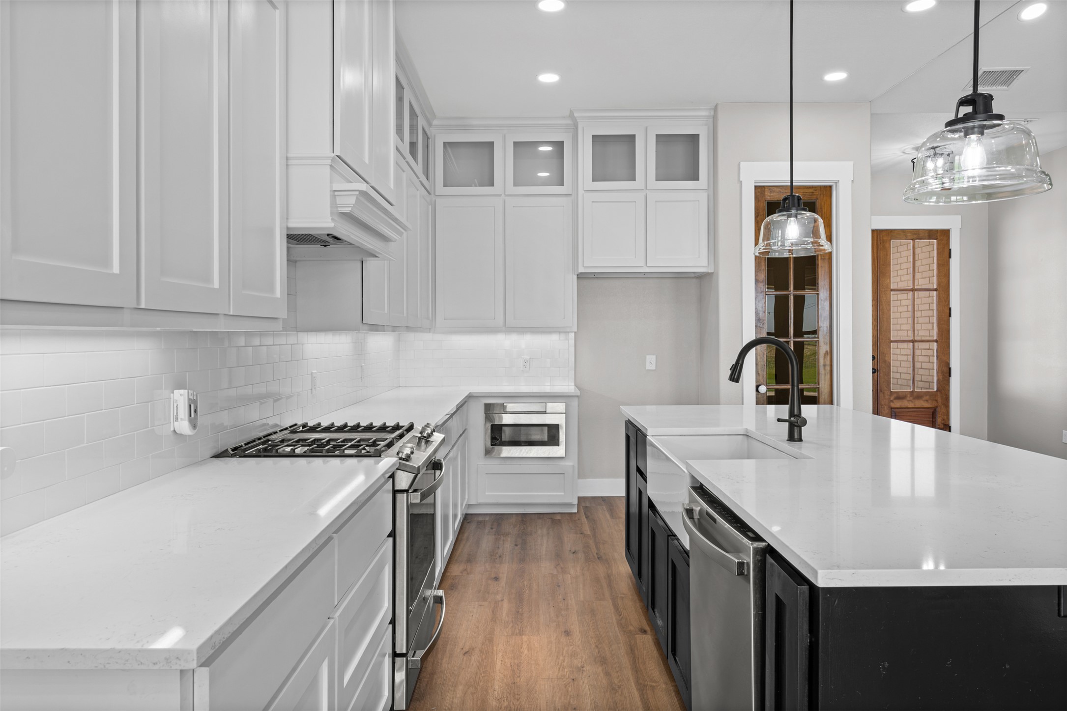 1060 Hackberry Road Salado, TX 76571 - Photo 8 of 19 Elegant quartz countertops and tall shaker cabinetry surround a central preparation island with custom lighting.