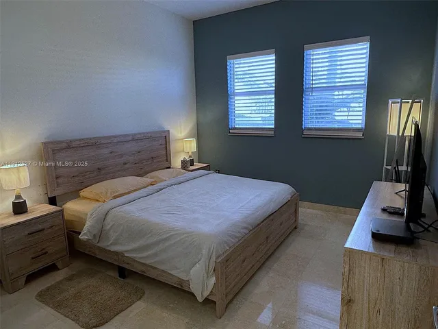 a bedroom with a bed a computer on the desk and a window