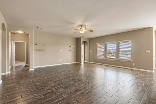 a view of an empty room with window and wooden floor