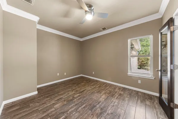 an empty room with wooden floor and windows