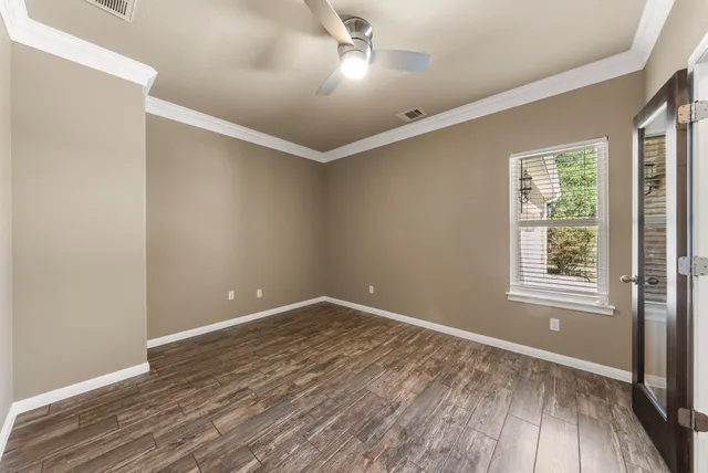 an empty room with wooden floor and windows