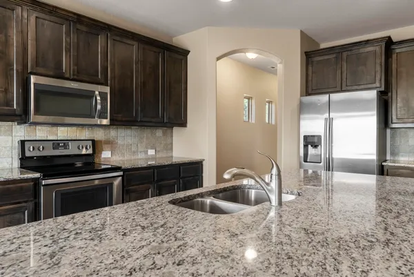 a kitchen with stainless steel appliances granite countertop a stove a sink and a microwave