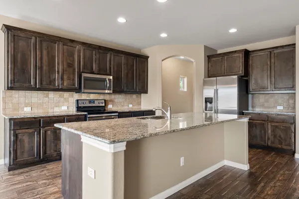 a kitchen with stainless steel appliances granite countertop a refrigerator a sink a stove a microwave and wooden cabinets