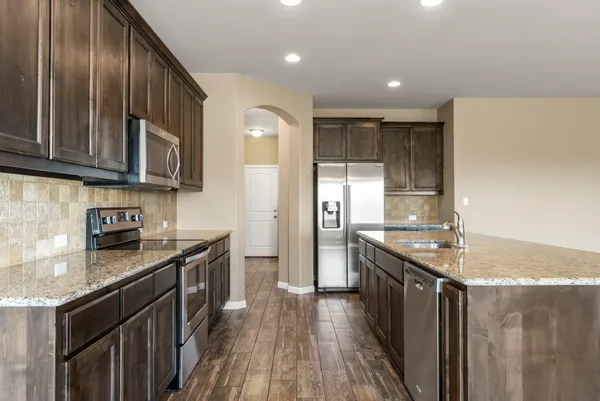 a kitchen with stainless steel appliances granite countertop a stove a sink and a refrigerator
