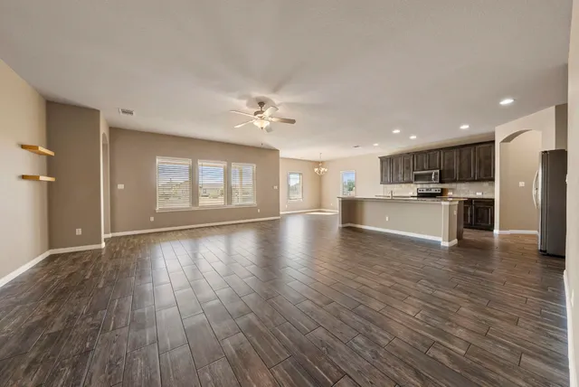 a view of an empty room with a kitchen and wooden floor