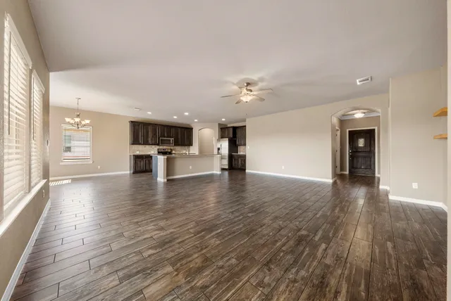 a view of an empty room and a kitchen with wooden floor and a kitchen
