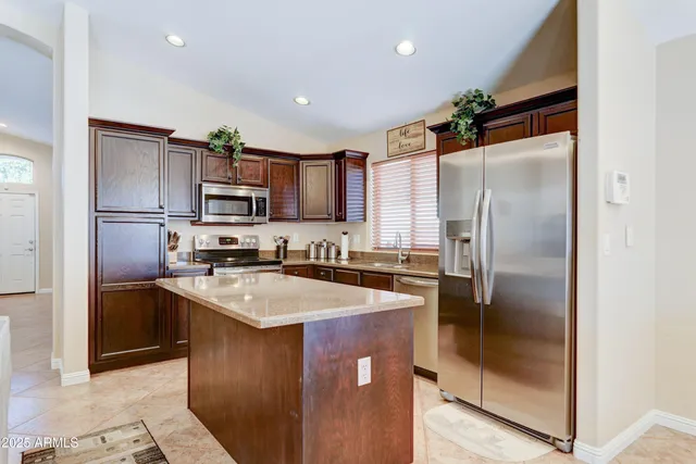a kitchen with kitchen island a counter top space cabinets and stainless steel appliances