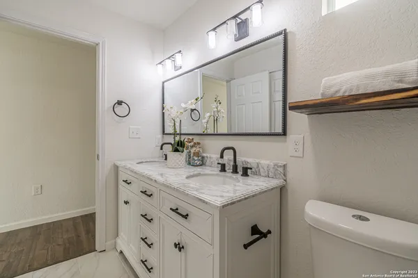 a bathroom with a granite countertop sink a toilet and a mirror