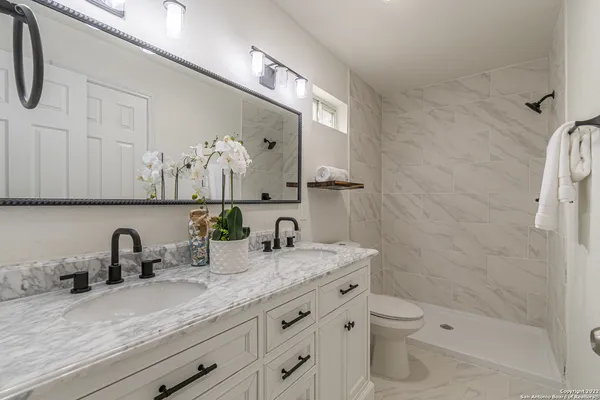 a bathroom with a granite countertop sink a toilet and a mirror