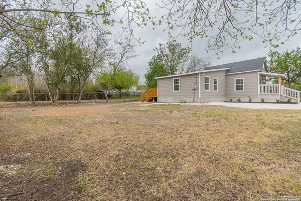 a backyard of a house with large tree and wooden fence