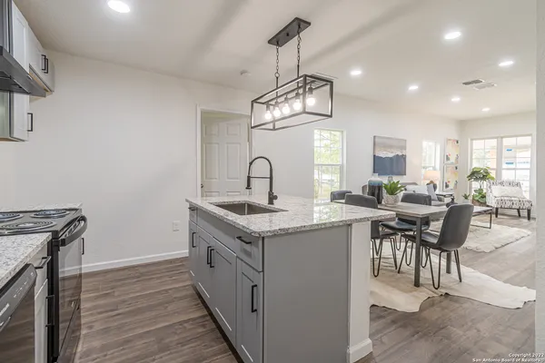 a kitchen with granite countertop a sink a stove top oven and cabinetry