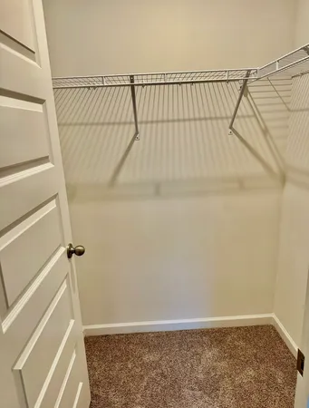an empty room with a chandelier fan and windows