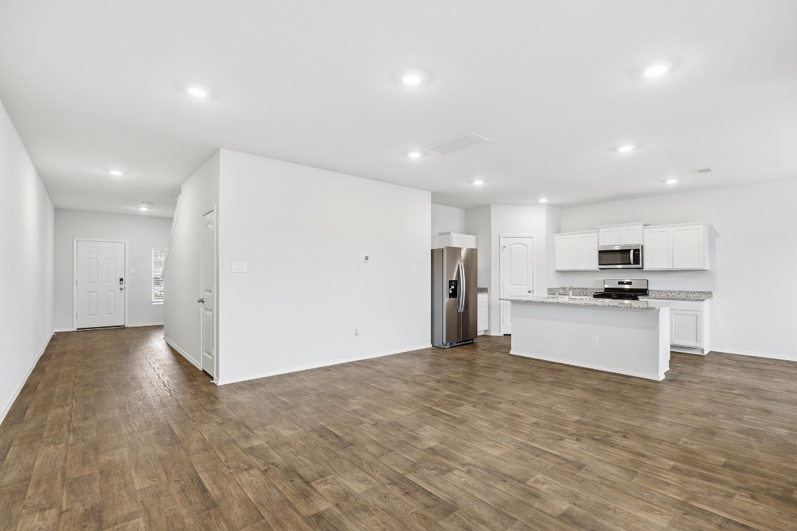 427 Sickle Loop Kyle, TX 78640 - Photo 38 of 39 Kitchen featuring stainless steel appliances, a kitchen island with sink, open floor plan, recessed lighting, and white cabinetry