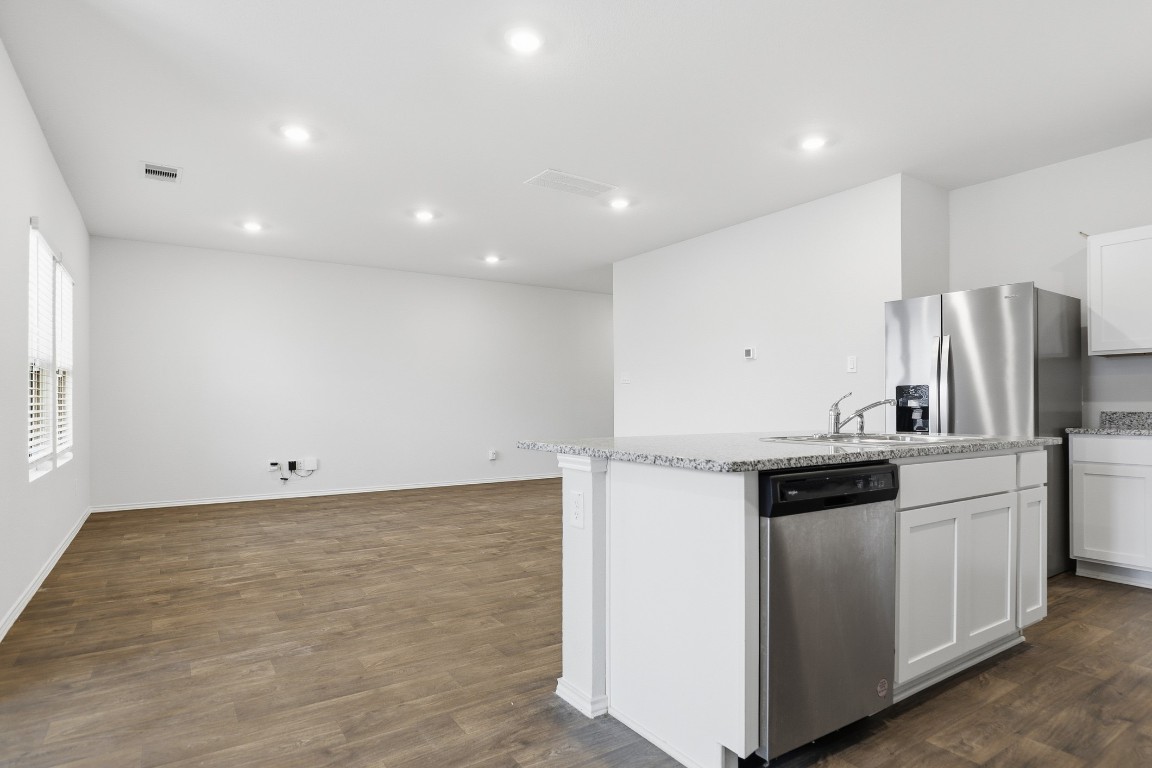 427 Sickle Loop Kyle, TX 78640 - Photo 28 of 39 Kitchen featuring stainless steel appliances, white cabinetry, light stone counters, dark wood-style flooring, and recessed lighting