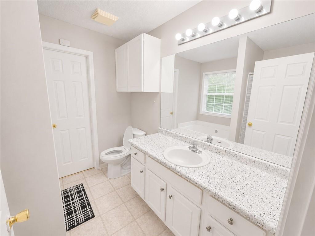 6936 Red Bone Way Stonecrest, GA 30038 - Photo 12 of 17 a spacious bathroom with a granite countertop sink a toilet and a mirror