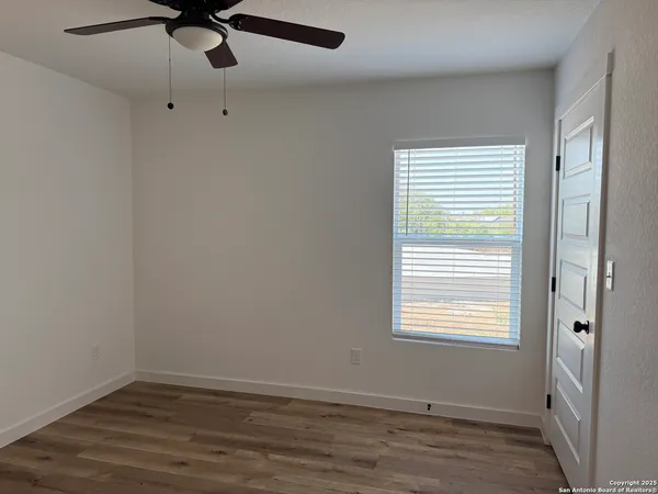 a view of an empty room with a window and wooden floor