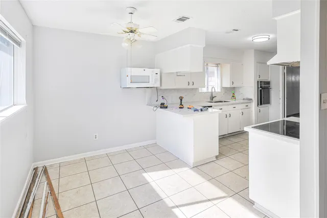 a kitchen with stainless steel appliances a sink a stove a refrigerator cabinets and living room view