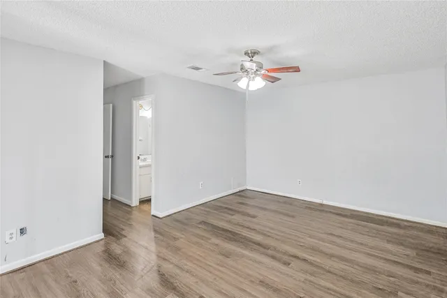 an empty room with wooden floor fan and window