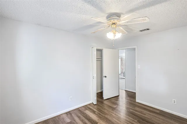 an empty room with wooden floor fan and windows