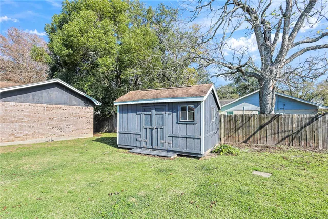 a view of a small house with wooden fence and a large tree