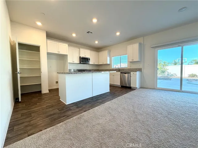 a kitchen with granite countertop white cabinets and black stainless steel appliances