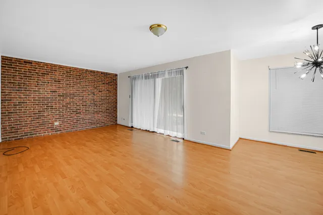 a view of an empty room with wooden floor and fan