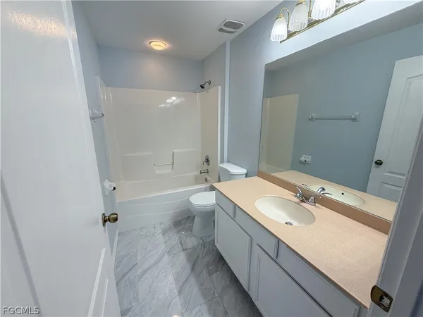 a bathroom with a granite countertop sink a toilet a mirror and bathtub