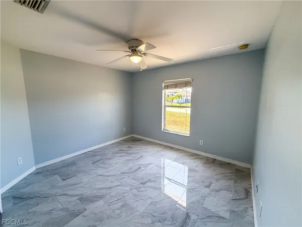 an empty room with windows and fan