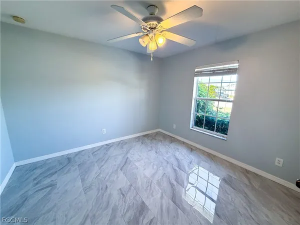 an empty room with a window and a fan