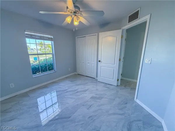 an empty room with windows and fan