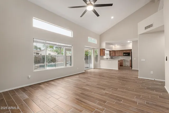 a view of an empty room with a window and wooden floor