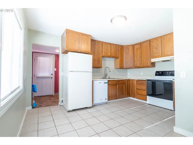 a kitchen with a refrigerator a stove top oven a sink and a window