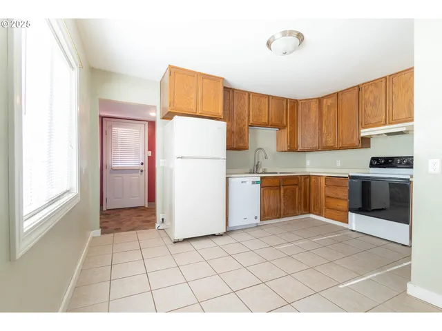 a kitchen with a refrigerator a stove top oven a sink and a window