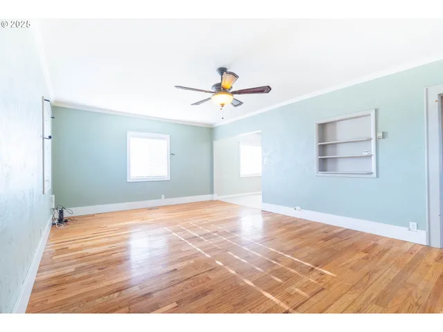 a view of an empty room with window and wooden floor